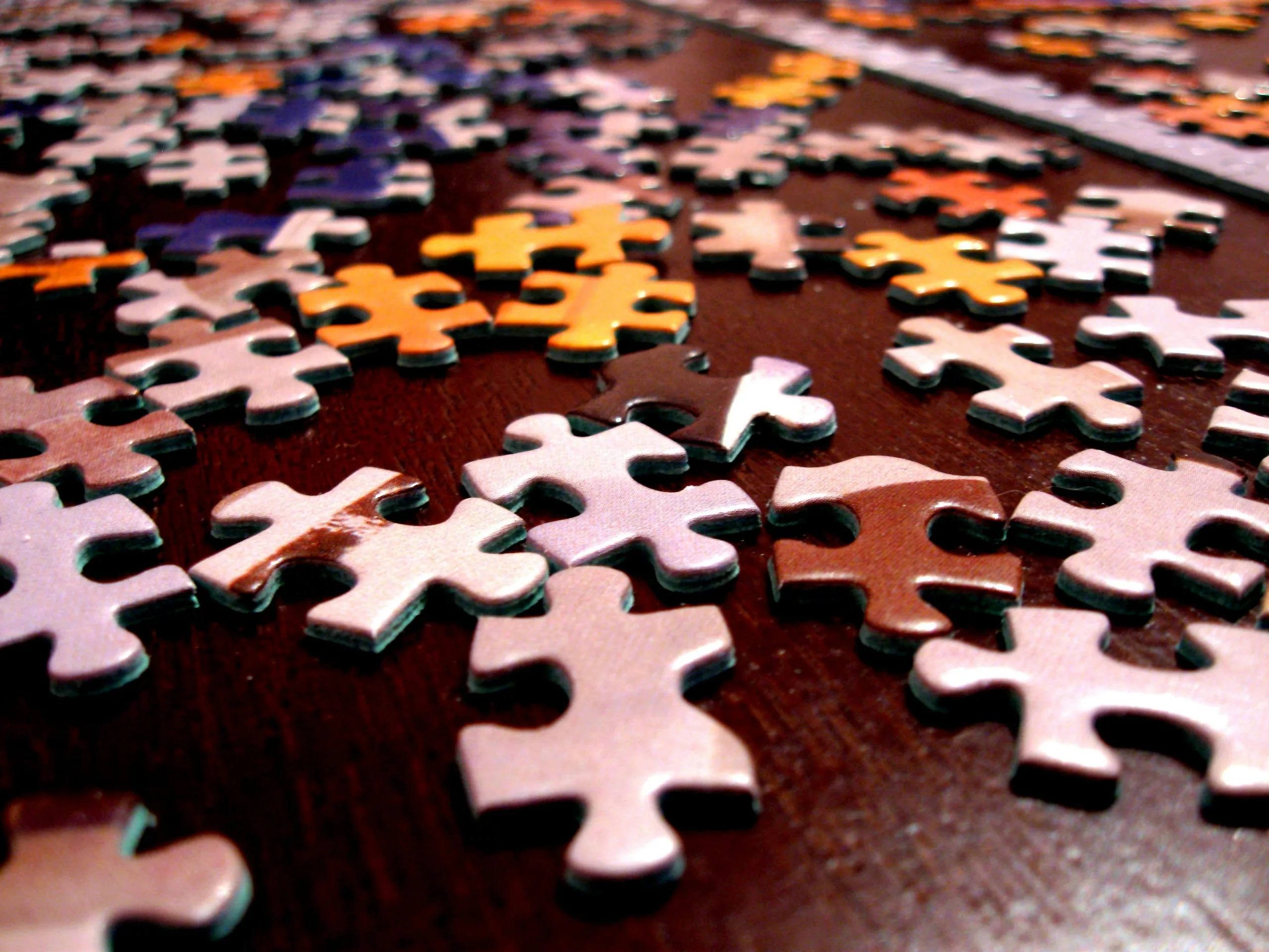 A pile of colorful puzzle pieces scattered on a table, representing the complexity of habit formation and the brain's ability to rewire itself through neuroplasticity.